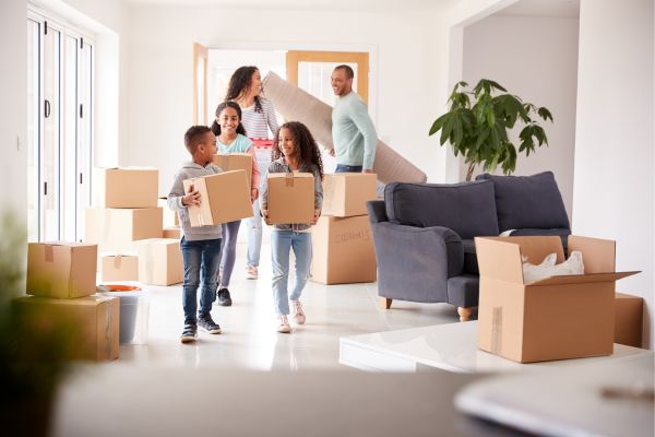 Smiling Family Carrying Boxes into New Home on Moving Day Smiling Family Carrying Boxes into New Home on Moving Day